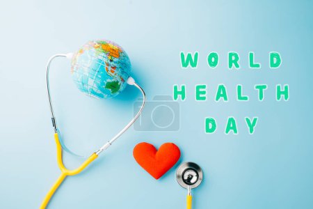 Foto de World Health Day. Yellow doctor stethoscope and world globe with Red heart shape isolated on blue background with copy space, Save world day, Green Earth Environment, Healthcare and medical concept - Imagen libre de derechos