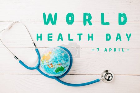 Photo for World Health Day. Top view doctor stethoscope wrapped around world globe isolated on wooden background with copy space for text, Save world day, Health care and medical concept - Royalty Free Image