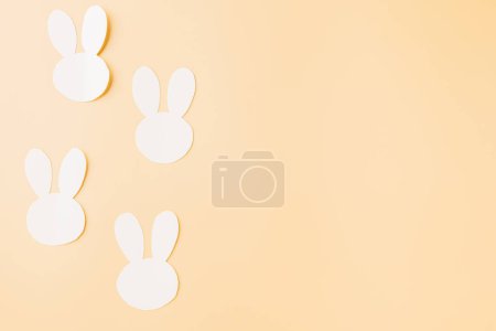 Téléchargez les photos : Concept du jour de Pâques. Découpe de lapin en papier blanc à la main isolée sur fond pastel avec espace de copie pour votre texte, Joyeuses vacances de lapin de Pâques, Conception de bannière pour le web - en image libre de droit
