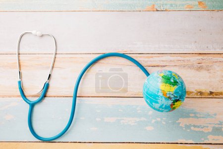 Foto de World Health Day. Top view blue doctor stethoscope wrapped around world globe isolated on white wood background with copy space for text, Global healthcare, Health care and medical concept - Imagen libre de derechos