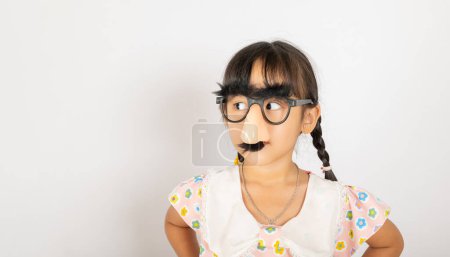 Photo for April Fools Day. Portrait of Funny kid little girl clown wears a big nos and glasses and has a mustache isolated on white background with copy space, Happy smile child festive decor - Royalty Free Image
