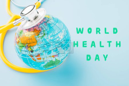 Téléchargez les photos : World Health Day Concept. Top view yellow doctor stethoscope and world globe isolated on pastel blue background with copy space, Save world day, Environment Green Earth, Health care and medical - en image libre de droit