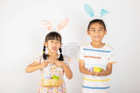 Photo for Happy Easter Day. Two smile Asian little girl and boy wearing easter bunny ears holding basket with eggs isolated on white background with copy space, Happy family children in holiday - Royalty Free Image