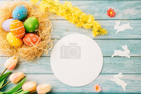 Photo for Happy Easter Day Concept. Flat lay of holiday banner background web design easter eggs in brown nest and blank paper circle on blue wooden background with empty copy space, celebration greeting card - Royalty Free Image