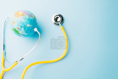 Photo for World Health Day. Yellow doctor stethoscope and world globe isolated on pastel blue background with copy space for text, Save world day, Green Earth Environment, Healthcare and medical concept - Royalty Free Image