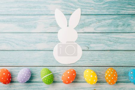 Téléchargez les photos : Easter Day Concept. Top view holiday banner background web design white colorful easter eggs and paper bunny rabbit on blue wood background with copy space, celebration greeting, overhead, template - en image libre de droit