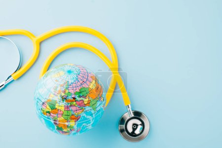 Foto de World Health Day. Yellow doctor stethoscope and world globe isolated on blue background, Save world day, Green Earth, Healthcare and medical concept - Imagen libre de derechos