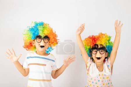 Photo for April Fools Day. Two brothers funny kid little girl clown wears curly wig colorful big nos and glasses and has mustache playing fool isolated on white background copy space, Happy child festive decor - Royalty Free Image