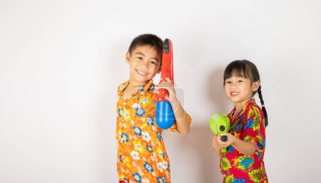 Téléchargez les photos : Happy Songkran Day, enfant asiatique fille et garçon tenant pistolet à eau en plastique, enfant thaïlandais drôle souriant tenir jouet pistolet à eau, isolé sur fond blanc, Thaïlande Songkran festival concept de culture nationale - en image libre de droit
