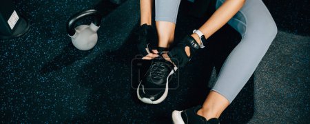 Foto de Primer plano de las piernas de una mujer mientras se ata los cordones de los zapatos antes de comenzar su rutina de ejercicios. La toma es perfecta para conceptos de fitness y salud. - Imagen libre de derechos