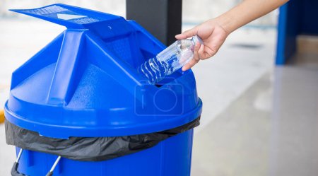 Foto de Cerca de la mano de la mujer tirar botella de agua de plástico vacía en la papelera de reciclaje, mujer tirar botella vacía a la basura, Reciclar basura, salvar el mundo y el cuidado del medio ambiente - Imagen libre de derechos
