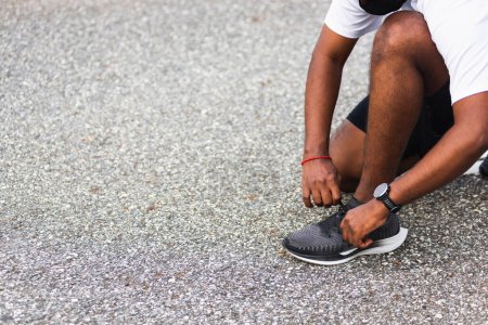 Photo for Close up Asian sport runner black man wear watch sitting he trying shoelace running shoes getting ready for jogging and run outdoor street health park with copy space, healthy exercise workout concept - Royalty Free Image