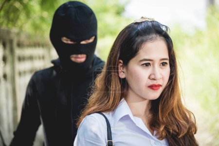 Photo for The robber holding a knife Is going to rob on back her while women are talking on mobile phone, Thieves were threatened following woman on the way she was walking home - Royalty Free Image
