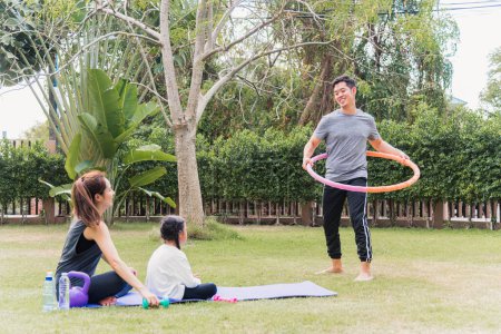 Foto de Asiática joven madre e hija practicando ejercicios de yoga al aire libre animar padre jugando con hula hoops en la naturaleza un parque de jardín de campo, deporte infantil familiar y ejercicios para un estilo de vida saludable - Imagen libre de derechos