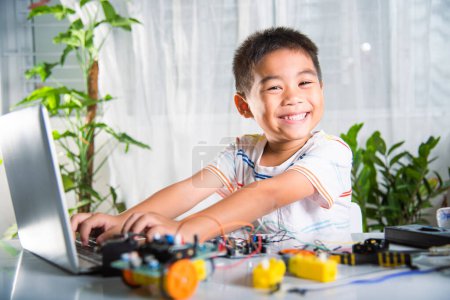 Téléchargez les photos : Enfant asiatique garçon apprend le codage et la programmation avec ordinateur portable pour voiture robot Arduino, Petits enfants élèves dactylographier le code dans l'ordinateur en ligne avec jouet de voiture, STEAM éducation AI technologie apprentissage de cours futur - en image libre de droit