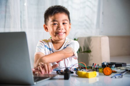 Foto de Niño asiático aprende codificación y programación con computadora portátil para el coche robot Arduino, Niños pequeños estudiantes escribiendo código en la computadora en línea con el juguete del coche, STEAM educación AI tecnología aprendizaje futuro curso - Imagen libre de derechos