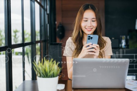 Photo for Happy lifestyle female smiling using smartphone in coffee shop, young business woman working with laptop computer she holding smart mobile phone looking out of windows at cefa for texting messages - Royalty Free Image