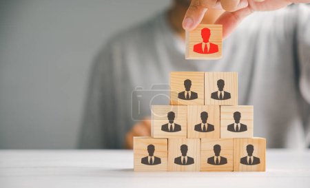 Photo for Hand holding and choosing man people icons on cube wooden toy blocks stacked. Represents the importance of human resources, teamwork, and effective leadership in achieving success. - Royalty Free Image