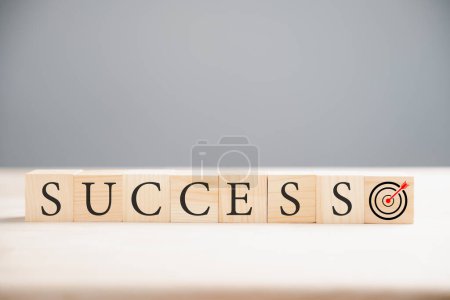 Photo for Abstract image of a wooden cube positioned above the word success on a wood table. Illustrating the concept of target success on a neutral grey background. - Royalty Free Image