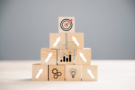 Photo for Cube wood blocks arranged with Target icon on top rise up arrows, representing growth. Bar graph chart steps on vertical symbolize a business growth process, signifying profit, investment, economic - Royalty Free Image