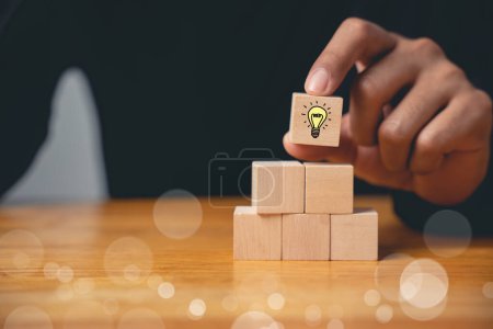 Photo for New idea and creativity concept. Wooden blocks with glowing light bulb icon on hand icon, suggesting inspiration and imagination with copy space. Designing innovative business solutions. - Royalty Free Image