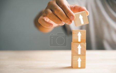 Photo for Hand arranging wood block stacking step stair with an upward arrow. Ladder career path for business growth and success process concept. Build your way up for increased revenue and personal development - Royalty Free Image