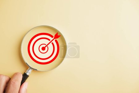 Photo for The magnifier glass focuses on a target board, highlighting the aim to achieve business objectives, it signifies the pursuit of excellence, achievement, and hitting the mark. - Royalty Free Image