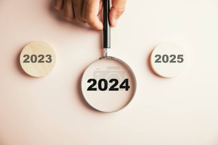 Photo for A magnifier focused on the 2024 icon, emphasizing the target business for upcoming year. It symbolizes planning, innovation, investment ideas transitioning from end of 2023 to the new year concept. - Royalty Free Image