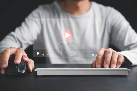 Téléchargez les photos : Plongez dans le monde du divertissement et de l'éducation en ligne avec un homme utilisant un ordinateur pour regarder des vidéos, diffuser du contenu et assister à des cours virtuels. - en image libre de droit