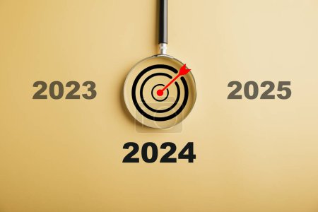 Téléchargez les photos : Une loupe se concentre sur l'icône de 2024, symbolisant l'entreprise cible pour l'année à venir. représente la planification, l'investissement et l'innovation au moment où les idées passent de la fin de 2023 au concept de nouvelle année. - en image libre de droit