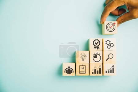 Photo for Hand arranging wood block stacking to depict the business strategy and action plan on blue background. Showcasing the concept of business development and targeting business goals. Copy space included - Royalty Free Image