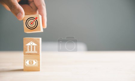 Photo for Wood block stacking guided by a hand symbolizes a strategic business plan and Action plan, focusing on the target. It represents business development and emphasizes growth and success. - Royalty Free Image