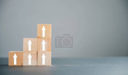 Photo for Wooden blocks with Target icon on top, surrounded by rise up arrows. Bar graph chart steps on blue background, representing vertical style of business growth process. Profit, investment, improvement - Royalty Free Image