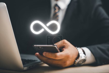 Photo for Businessman presents smartphone with infinity symbol, signifying limitless connection in data technology, future unlimited. Infinite power, energy, internet information. technology infinity data - Royalty Free Image
