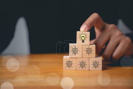 Photo for Expertise and support concept. Wooden cubes with light bulb icon on hand icon, suggesting a solution with copy space. Consultation for business development and growth. - Royalty Free Image