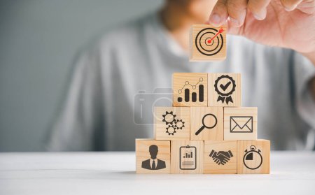 Photo for Businessmans hand stacking wooden blocks on a table, highlighting the importance of a business strategy and action plan. Conceptual image of business development. Copy space provided. - Royalty Free Image