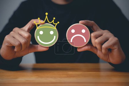 Photo for Customer satisfaction survey concept, a mans hand selecting a smiley face on a wooden block circle to indicate excellent service and experience. - Royalty Free Image