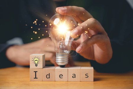 Photo for Insight and discovery concept. Person holding wooden block with light bulb icon, suggesting a breakthrough with copy space. Business intelligence for productive transformation. new ideas - Royalty Free Image