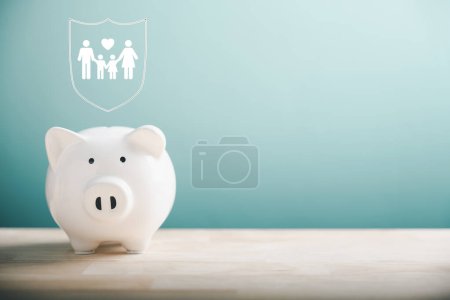 Photo for Piggy bank, family icon nearby, on desk. Family life insurance concept. Symbolizing financial security, safe education, health budget, and wealth accumulation. Representing family economic well-being. - Royalty Free Image