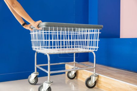 Photo for Laundry and housework. metal cart parked use for laundry at convenience store for support customer, Woman hands holding shove empty new white trolley cart, Laundromat convenience store concept - Royalty Free Image