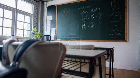 Photo for Empty classroom with chairs elementary school desks and chalkboard, Interior of a school class room with table and blackboard at high school, Education Institution in the daytime - Royalty Free Image