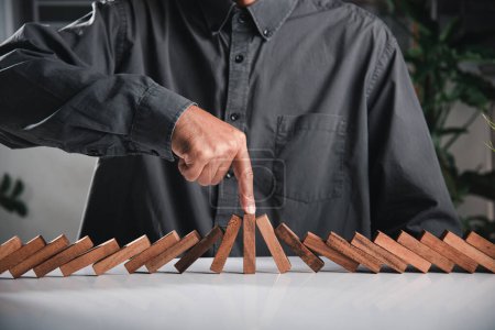 Photo for Finger of businessman pointing one wooden to stopping domino effect stopped, Close up hand stopping or preventing falling block in line with risk, Risk protection concept - Royalty Free Image