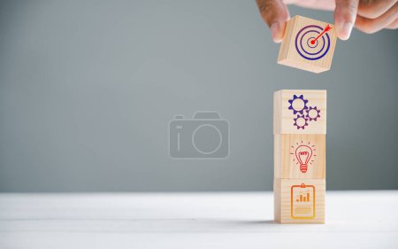 Photo for Wood block cube held by hand, featuring an icon that represents company strategy development. Conceptual image of achieving success and business goals. - Royalty Free Image