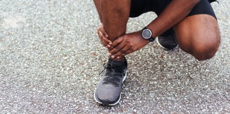 Photo for Close up Asian young sport runner black man wear watch hands joint hold leg pain because of twisted ankle broken while running at the outdoor street health park, healthy exercise Injury from workout - Royalty Free Image