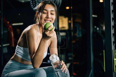 Photo for A fitness trainer holds a green apple in a gym, emphasizing the importance of proper nutrition and healthy food choices for achieving fitness goals. Healthy fitness and eating lifestyle concept - Royalty Free Image
