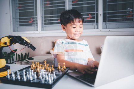 Foto de Asian little boy programming code to robot machine arm on laptop for play chess, STEM education E-learning, Funny children learning getting lesson control robot arm, Technology science education - Imagen libre de derechos