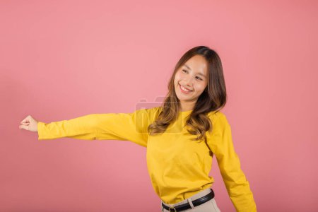 Foto de Asian young woman dancing with inspired face expression and raising hands up, Portrait of happy female model jocund in sneakers dancing, studio shot isolated on pink background, Time to relax - Imagen libre de derechos