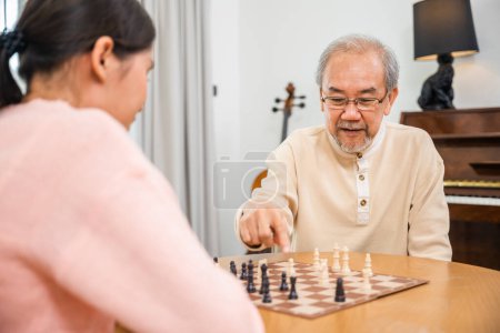 Foto de Smiling senior elderly having fun playing chess game with beautiful daughter at home, nurse caregiver in nursing home for leisure, Happy active retired people, Healthcare and medical homecare concept - Imagen libre de derechos