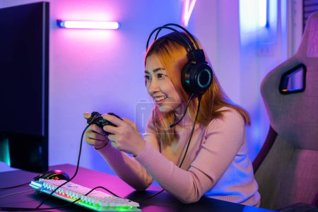 Téléchargez les photos : You win. Gamer using joystick controller plays online video game with computer neon lights very determined, woman wear gaming headphones playing live stream esports games console at home - en image libre de droit