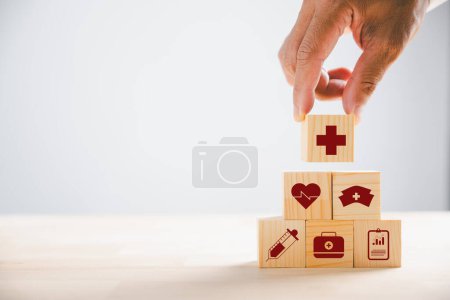Photo for Hand grasping wooden block displaying healthcare and medical icons. Conveying safety, health, and family well-being. Representing pharmacy, heart care, and happiness. health care concept - Royalty Free Image